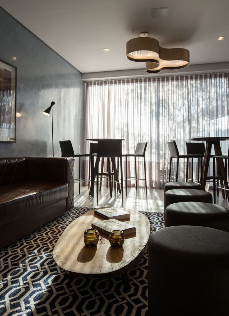 Living room lit with natural light, decorated with sofas, benches, tables and stools, and Accord pendant in the center.